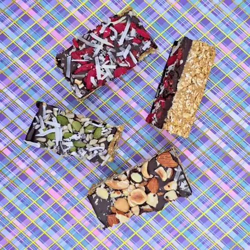 Portioned pieces of the chocolate chickpea slice. Toppings included. Mixed seeds and coconut, goji berries and coconut and mixed nuts.